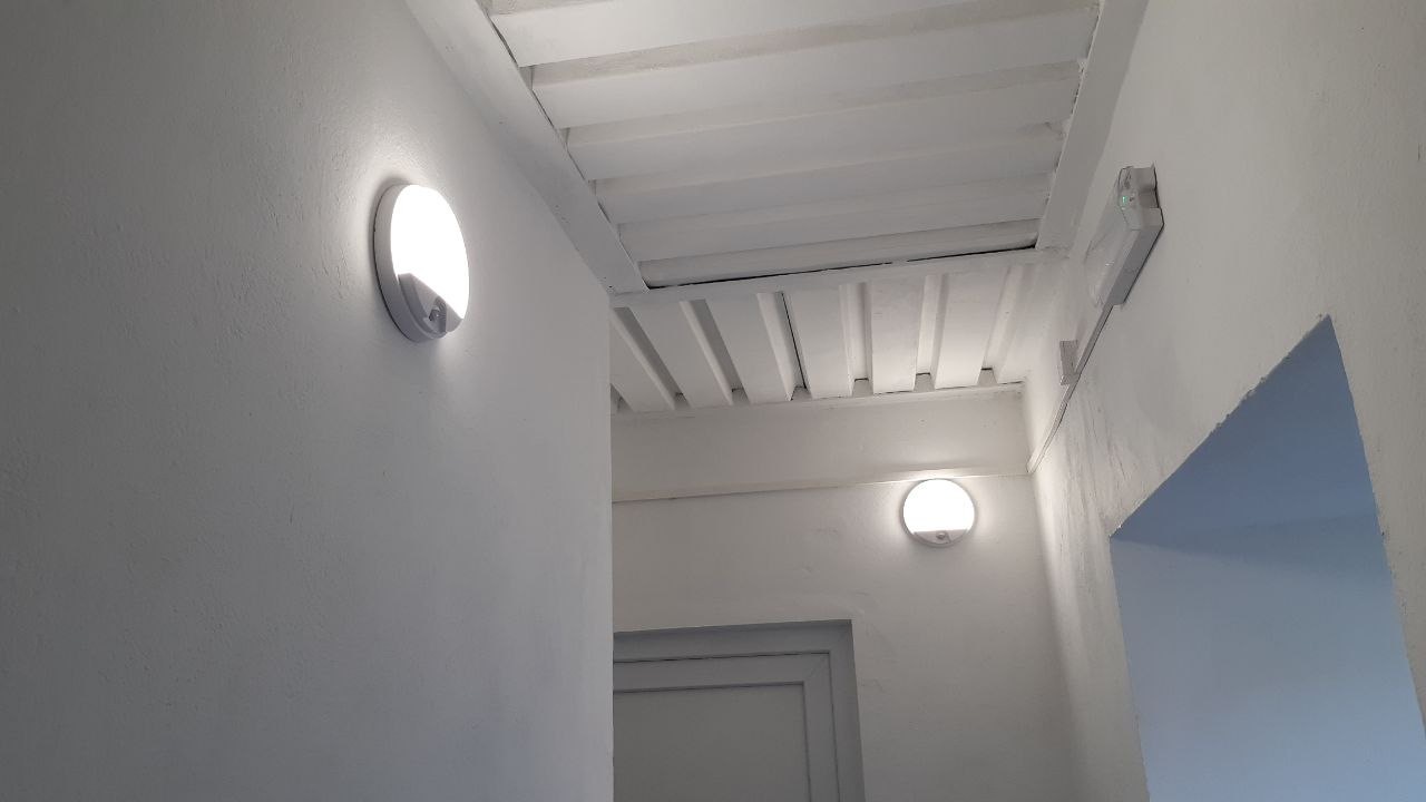 Chodba se dvěma rozsvícenými nástěnnými svítidly